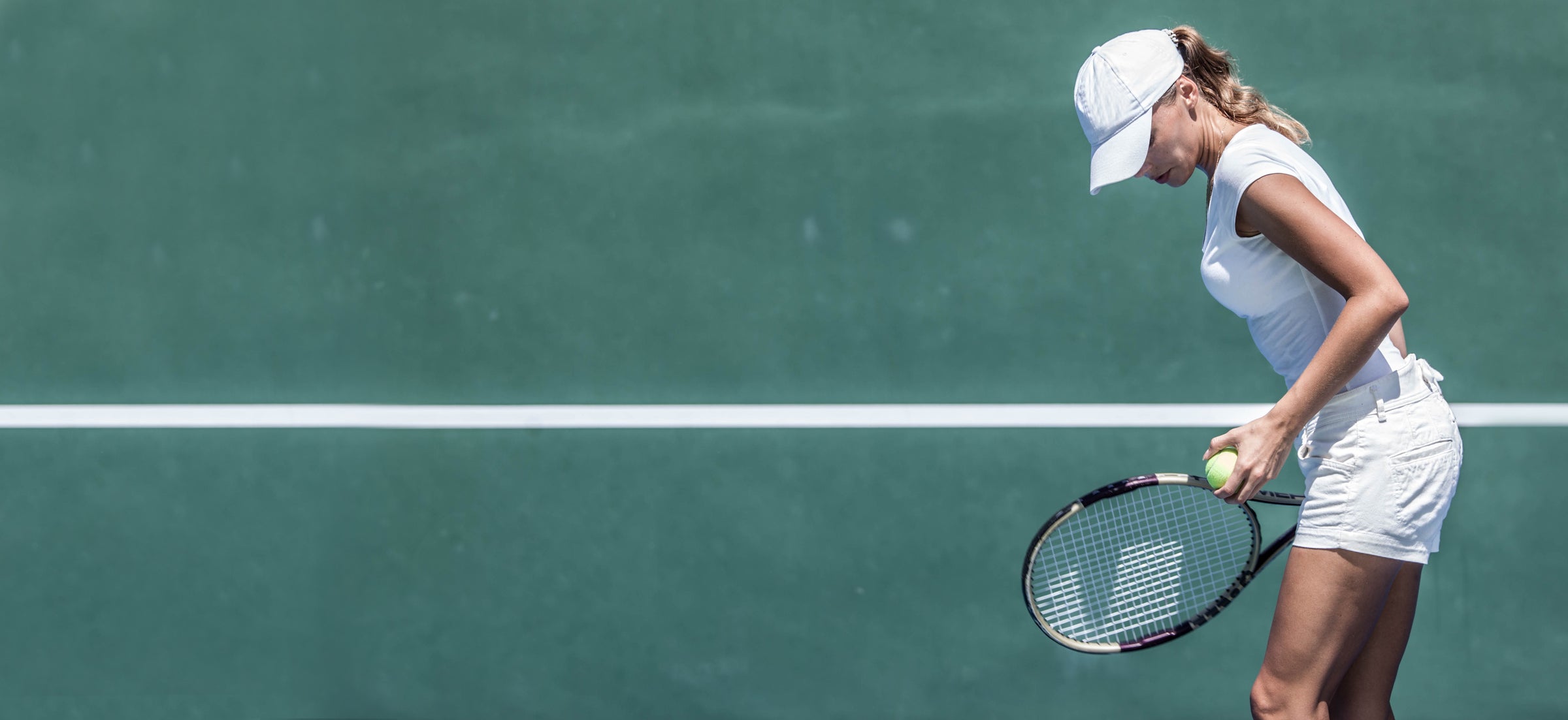 Woman serving on a green tennis court