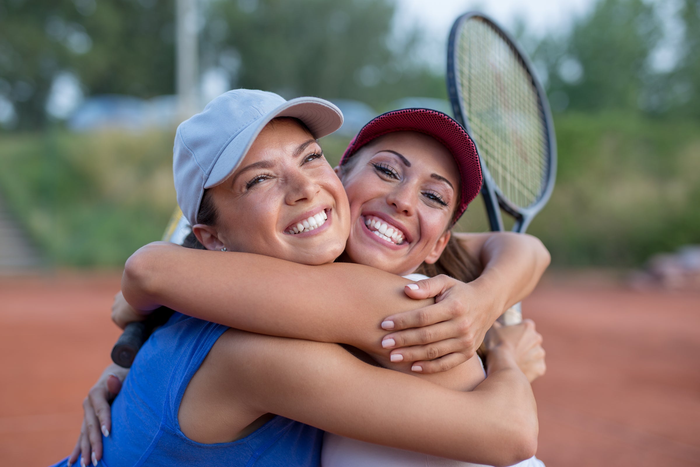 Two women laughing with rackets after a doubles match